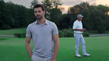 Gülümseyen golfçü aktivite kursunda oynamayı sever. Sporcular golf kulübünde rahatlar..