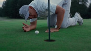Profesyonel golfçü yeşil çimen sahasında golf topu deliğini inceliyor..