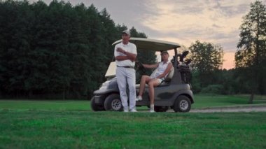 İki golfçü golf sahasında dinleniyor. Evli çift golf arabasında rahatlar..