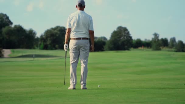 Dışarıda golf sahasında tek başına duran bir adam. Sporcu yazın temiz havanın tadını çıkarır.. — Stok video