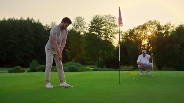 Sportovní muži hrají golf na hřišti. Golfový tým tráví čas v luxusním resortu. — Stock video