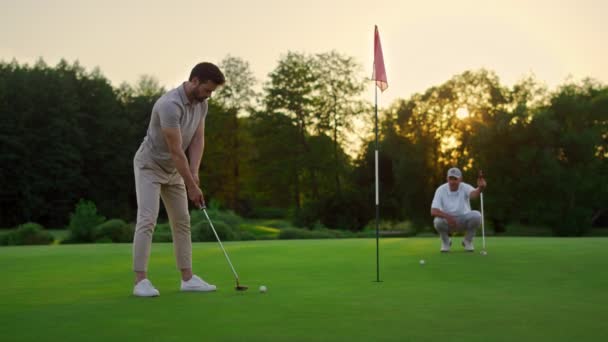 Golfers team slagbal op zonsondergang veld natuurlijk. Twee spelers missen golfschot. — Stockvideo