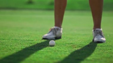 Yeşil sahada golf oynayan sportif kadın bacakları. Golf treni golf sahasında topa vuruyor..