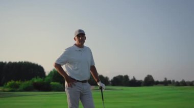 Üst düzey poz veren golf sahası. Golf sahasında kameraya bakan zengin bir adam. Elinde golf sopası olan neşeli bir emeklinin golf sahasında spor aletleri. Golfçü hafta sonu vakit geçiriyor. Lüks hobi konsepti