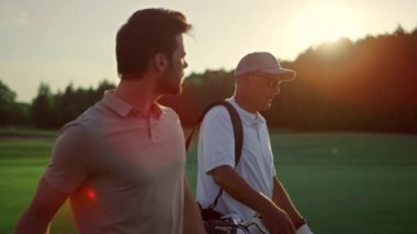 Golf oyuncuları yaz sahasında gün batımına bakıyor. Golfçüler grubu dışarıda golf sahasında yürüyor. İki golfçü, lüks tatil haftasonunda spor faaliyetlerinin keyfini çıkarıyorlar. Rahatla hobi eğlence oyun konsepti