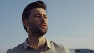 Dışarıda konuşan yakışıklı bir adam. Bulutsuz gökyüzünde poz veren sakallı iş adamı. Kafkasyalı bir adamın portresi lüks bir hafta sonu geçirmekten zevk alıyor. Zarif stil yetişkin yüzü güzellik konsepti