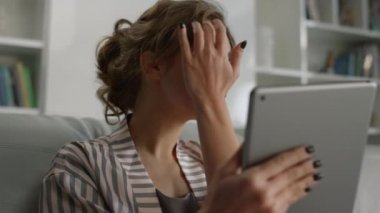 Kadın el ile saç dudaklarına dokunuyor. Kız video çekimine hazırlanıyor. Serbest çalışan, tablet bilgisayar ekranına odaklan ve kendine hayran ol. Çekici kız kanepeye otur ve online randevuya hazırlan..