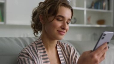 Gülümseyen kız sabah internetten alışveriş yapıyor. Çekici bir bayan arkadaşa mesaj atıp sosyal medya uygulamasını evde kaydırıyor. Neşeli kadın pijamalarıyla internette sörf yapıyor. Kanepede bir aletle dinleniyor..