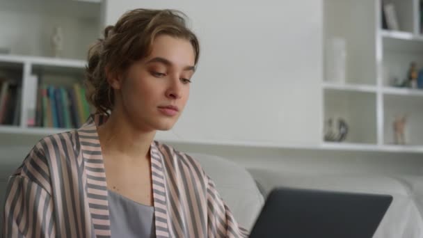 ノートパソコンを使って家で働くスリーピーマネージャー 家の近くであくびをしている疲れた女性 美しい若い女性のブロンドのフリーランサーは リモート職場でコンピュータを入力記事を作成します 残業の考え方 — ストック動画