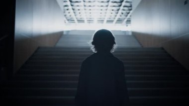 Rahat genç silueti parlak ışıkta tek başına yukarı çıkıyor. Sınıftan sonra modern boş merdivenlerde yürüyen tanınmayan genç öğrenci. Okul binasının arkasında gezinen yalnız okul çocuğu..