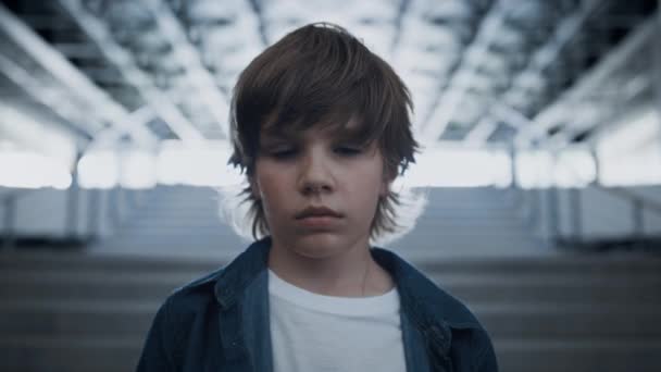 垂头丧气的十多岁男孩独自站在学校的楼梯近旁 小学生在冲突后感到很不快乐 一个孤独的少年认真地看着相机 孤独的童年概念 — 图库视频影像