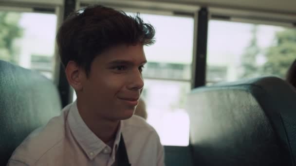 学校のバスの中で話しているインドの少年の笑顔を閉じます 幸せな多文化学生の肖像車の輸送座って 同級生とおしゃべりする楽しいブルネットの少年 リラックスした十代の若者たち楽しみます乗り心地 — ストック動画