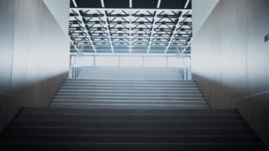 Boş okul merdivenleri büyük salona çıkıyor. Çelik parmaklık manzaralı temiz merdiven. Geniş pencerelerde parlayan güneş ışığı. Eğitim kurumunun tavanında lambalar var. Modern inşaat kavramı.