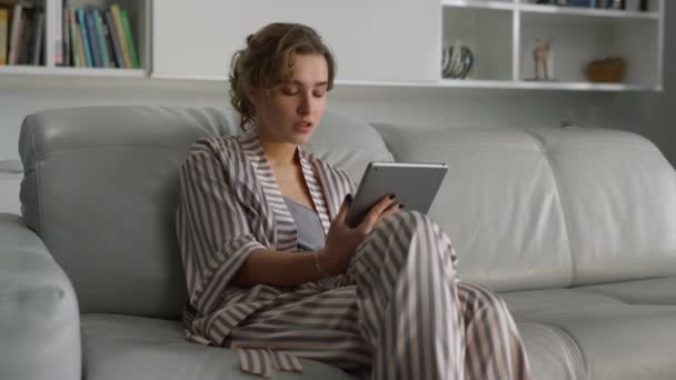 心烦意乱的女孩在客厅里拿着垫子电脑 经理远程处理平板电脑 可悲的成功女商人浏览社交媒体阅读新闻 穿着睡衣在网上购物的漂亮女人很失望 — 图库视频影像