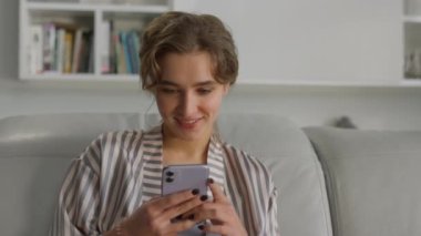 Cep telefonu portresinden mesaj atan mutlu kız. Kanepede akıllı telefon kullanan bir uygulama kullanıcısı. Oturma odasında gülümseyen öğrenci sohbeti. Neşeli güzel bayan, sabah sörfünün tadını çıkar.