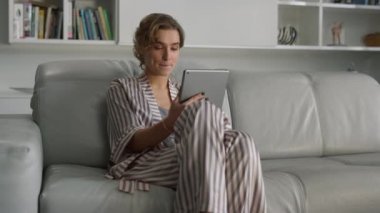 Neşeli kız evde video görüşmesi yapıyor. Tablete el sallayan gülümseyen kadın. Mutlu güzel kadın blogcu çevrimiçi video kaydı hakkında konuşmaktan zevk alıyor. Uzak bir iş yerinde çekici bir iş kadını çalışıyor.