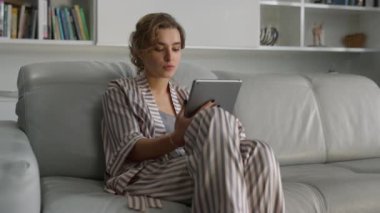 İş sahibi tabletten e-postayı kontrol ediyor. Ciddi bir kız hafta sonu evde dinleniyor. Dijital bilgisayarla kanepede çalışan çekici bir kadın. Oturma odasında internette gezinen güzel odaklı serbest yazar.