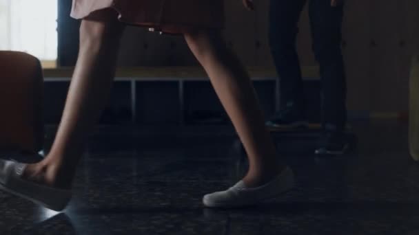 在课间休息的时候 女学生的脚在学校大厅里走着 未被承认的未成年女学生穿着经过各种各样活跃学童的衣服 穿着白运动鞋的学生小腿踩地 — 图库视频影像