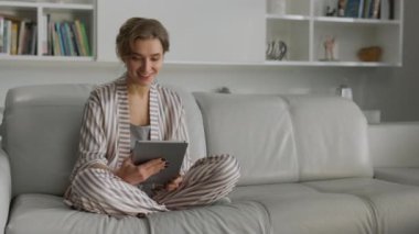 Öğrenci oturma odasında çevrimiçi video konuşması yapıyor. Koltukta çalışırken ped kullanan gülümseyen kız. Mutlu kadın, yeni evimizin içini nöbetçi olarak gösteriyor. Çekici bayan taşındıktan sonra evinde dinleniyor.