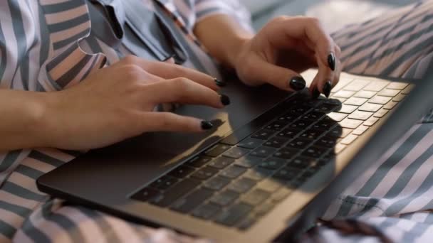 パジャマの閉鎖でノートパソコンの残業を管理してる 自宅のランプライトにキーボードを入力する女の子の手 夜遅くに作文を勉強している無名の学生 ベッドでインターネットのソーシャルメディアをサーフィン女性 — ストック動画