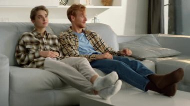 Evli çift birlikte dinleniyor. Kızıl saçlı koca televizyon kanalını araklıyor. Genç bir aile televizyon izleyip, iç mekanda dizi seçiyor. İki mutlu arkadaş film haftasonunda takılıyorlar..