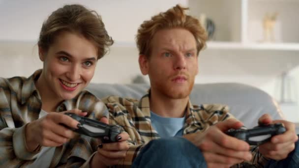 快乐的妻子在家中与红头发的丈夫手握游戏垫打斗 让人困惑不已 兴奋的女人享受着与沮丧的姜人的虚拟竞争 朋友们周末用操纵杆玩电子游戏 — 图库视频影像