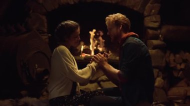 Genç insanlar şöminenin yanında el ele tutuşuyorlar. Romantik çift balayını akşam buluşmalarında geçirir. Evli aşıklar tatil zamanlarında ilişki kurmaktan hoşlanırlar. Kız arkadaş erkek arkadaş birbirine bakıyor. Aşk konsepti.