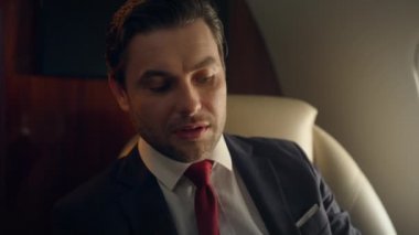 Kendine güvenen iş adamı jet kapanışı yapıyor. Zengin beyefendi lüks takım elbise içinde seyahat eder. Yakışıklı başarılı yönetici şirket seyahati sırasında partneriyle konuşuyor. Birinci sınıfta zarif bir profesyonel uçuş.
