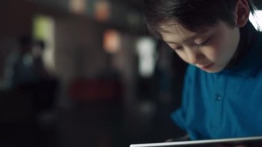 Okul koridorunda tablet sörf interneti kullanan meraklı öğrenciyi kapatın. Tek başına online oyun oynayan küçük bir çocuğa kafayı takmış. İlkokul çocuğu arkadaşları görmezden geliyor ve tatilde eğleniyor.. 