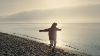 Heyecanlı bir kadın plajda dönüyor. Deniz kenarında dans eden mutlu kız. Okyanus kıyısında atlayan hippi bir kadın. Zarif bir kadın el kaldırıyor. Genç bayan dışarıda mutlu. Gün doğumunda deniz manzarası