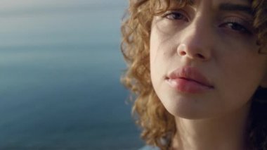 Yakın plan, üzgün kadın denizde kameraya poz veriyor. Ciddi yüz ifadesi olan neşeli bir kız. Kadın model göz kırpıyor. Odaklanmış kadın hareket ediyor. Okyanus sahilinde hüzünlü bir kadın portresi. Duygu kavramı 