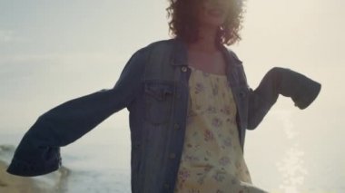 Sahilde kameraya poz veren oyuncu kız. Kumsalda gülümseyen bir kadın. Kadın model el kaldırıyor. Özgürlüğü hisseden mutlu kadın. Şık elbiseli hippi kız. Moda konsepti