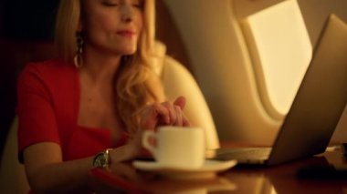Şirket gezisinde çalışan güzel bir bankacı. Eller yakın çekim rampasına. Gülümseyen muhteşem sarışın dizüstü bilgisayarla satış istatistiklerini kontrol ediyor. Zarif zengin iş kadını seyahat jeti.