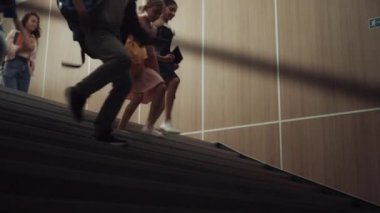 Alt kattaki karanlık okul koridorunda koşuşturan bir grup genç. Çocuk bacakları merdivene basıyor. Yaklaş. Merdivenlerden inen enerjik mutlu okul çocukları. Dersten sonra çeşitli öğrenciler birlikte koşuşturuyor.