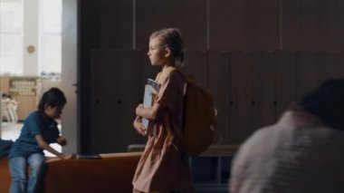 Küçük gergin kız okul tatilinde canlı koridorda tek başına yürüyor. Sırt çantalı endişeli liseli kız elinde kitaplarla karanlık salona gidiyor. Koridorda enerjik çeşitli öğrenciler oynuyor. Çocuklukta yalnızlık.