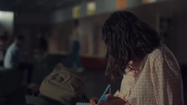 活気のある学校のブレークアップに才能のある女子学生のスケッチを描く 日記にメモを書いて座っている10代の少女に焦点を当てた ブルネットティーン作る宿題で廊下フル多様な学生 — ストック動画
