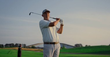 Sahada golf oynayan heyecanlı bir golfçü. Zengin son sınıf sportif aktiviteler yapıyor. Yaşlı beyaz oyuncu golf sahasında topa vuruyor. Yaşlı adam hafta sonu gösteri yetenekleri sergiliyor. Boş zaman konsepti
