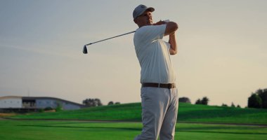 Golf oyuncusunun golf sopası spor antrenmanında. Zengin adam dışarıda lüks bir tatilde eğleniyor. Odaklanmış golfçü, aktif emekliliğin tadını çıkarıyor. Golfçü oyunda topa vuruyor. Varlıklı konsept