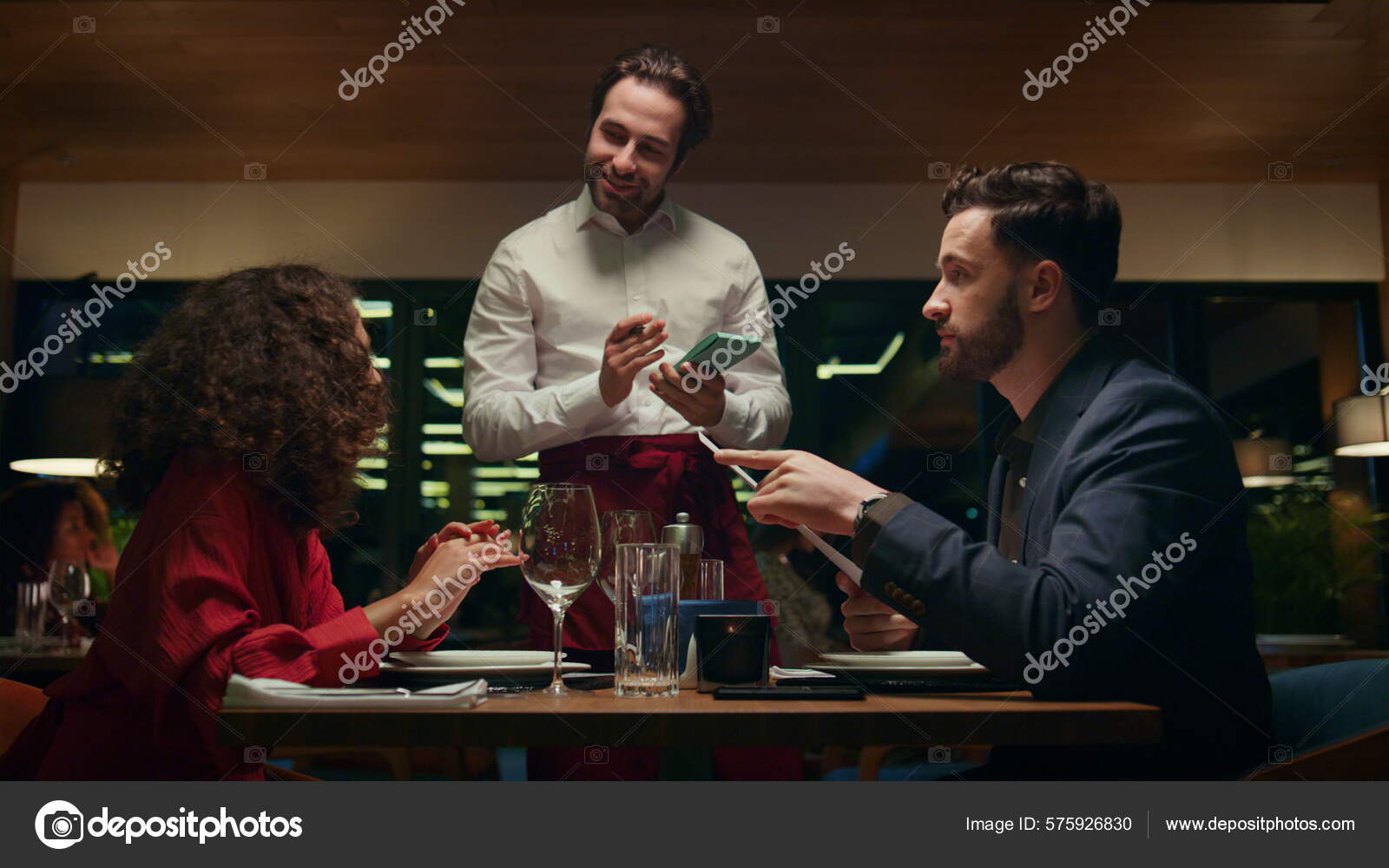Smiling Waiter Serving Multiracial Couple Restaurant Date Mixed Race Young Stock Photo by ©stockbusters 575926830 picture