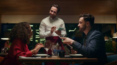 Gülümseyen garson restoran randevusunda çok ırklı çifte servis yapıyor. Otelin barında oturan melez genç aşıklar. İki kişi süslü İtalyan kafe masasında menü siparişi veriyor. Romantik yemek konsepti.