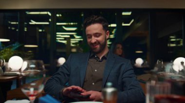 Lüks restoran masasında akşam yemeğini ödeyen adam. Kafede pahalı görünen mutlu iş adamı. Yakışıklı beyefendi yemek yerinde cep telefonu nakitsiz kontak ödemesi kullanıyor. Yemek konsepti.