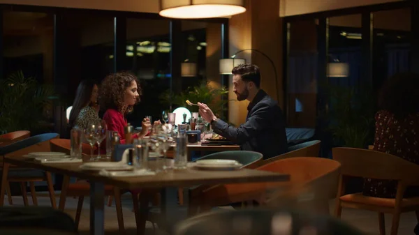 Loving couple eating together at fancy restaurant table. Two multiethnic people share delicious italian food on romantic dinner date. Lovers spend time on anniversary celebration at cafe. Love concept