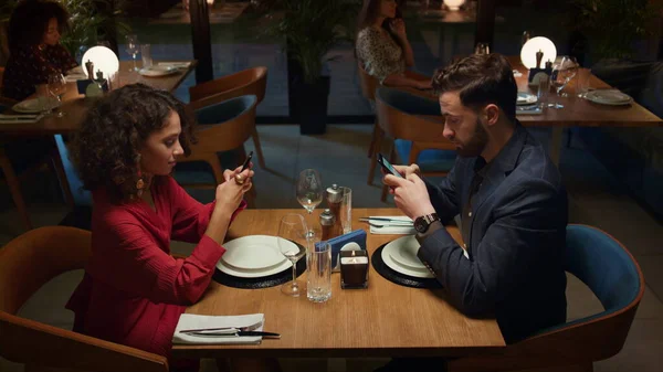 Mixed race couple ordering food online at fancy restaurant table on romantic evening date. Two lovers looking online cafe menu together. Love partners scrolling web internet. Technology device concept