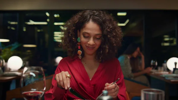 African american girl eating tasty meal in fine dining place. Gorgeous woman enjoying dinner in italian fancy restaurant. Young pretty lady looking camera on date concept. Romantic tasty meal concept.