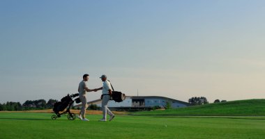 Golfçüler grubu yeşil sahada buluşmayı sever. İki sporcu dışarıda el sıkışıyor. Golf takımı hafta sonu lüks tatil köyü aktivitelerinde aktivite eğitimi alıyor. Eğlence hobisi eğlence konsepti.