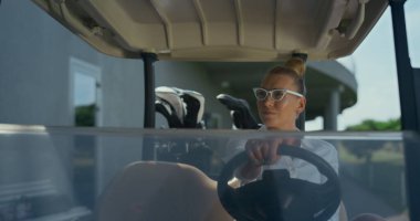 Golf sahasında yürüyen bir kadın. Golfçü güneşli günün tadını çıkarıyor. Dışarıda golf arabasında oturan kendinden emin bir profesyonel antrenör. Çekici bayan müşteri bekliyor. Spor konsepti