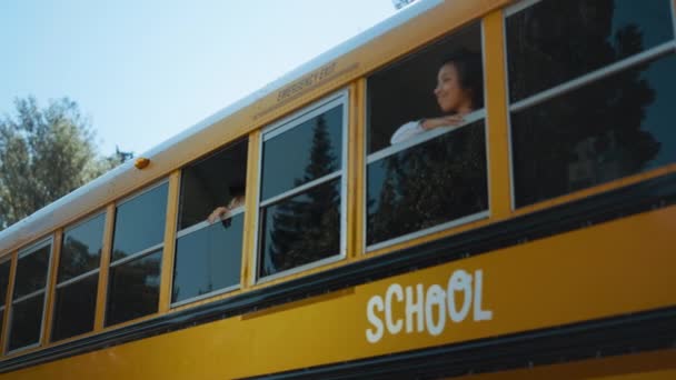 两名小学生早上从公共汽车窗口往外看 站在校车上的多民族微笑小学生准备上学 卷曲的男孩 带着快乐的女孩同学看相机 — 图库视频影像