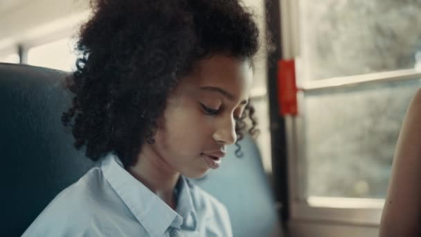笑非裔美国女学生看相机在学校的校车关闭 快乐快乐的女孩 卷曲的头发在窗前摆姿势 可爱的黑发学生享受与朋友的路上旅行 童年概念 — 图库视频影像