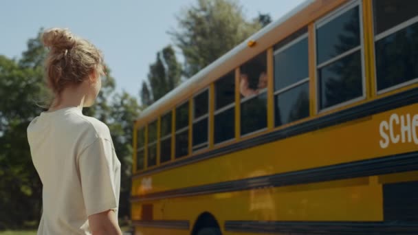 Маленький Хлопчик Дивиться Шкільне Вікно Автобуса Махає Мамі Стоячи Вулиці — стокове відео