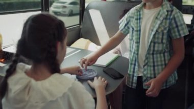 Okul otobüsüne binen çok ırklı grup çocukları. Neşeli çocuklar araç nakliyatında popit oynuyorlar. Neşeli ergen öğrenciler birlikte iletişim kurarken eğleniyorlar. Kamu eğitim ulaşım kavramı.